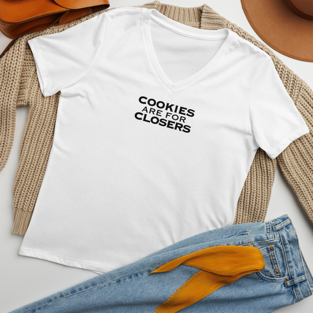 "Cookies Are For Closers" printed on a solid white blend women's relaxed v-neck t-shirt laying on a flat surface amongst other clothes