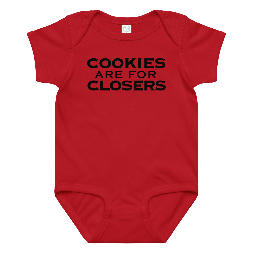 "Cookies Are For Closers" printed on a red baby jersey bodysuit laying on a flat surface amongst other clothes