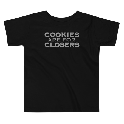 "Cookies Are For Closers" printed on a black toddler short sleeve tee laying on a flat surface