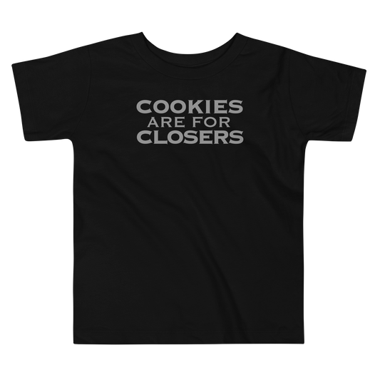 "Cookies Are For Closers" printed on a black toddler short sleeve tee laying on a flat surface