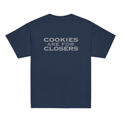 "Cookies Are For Closers" printed on a navy youth classic tee laying on a flat surface