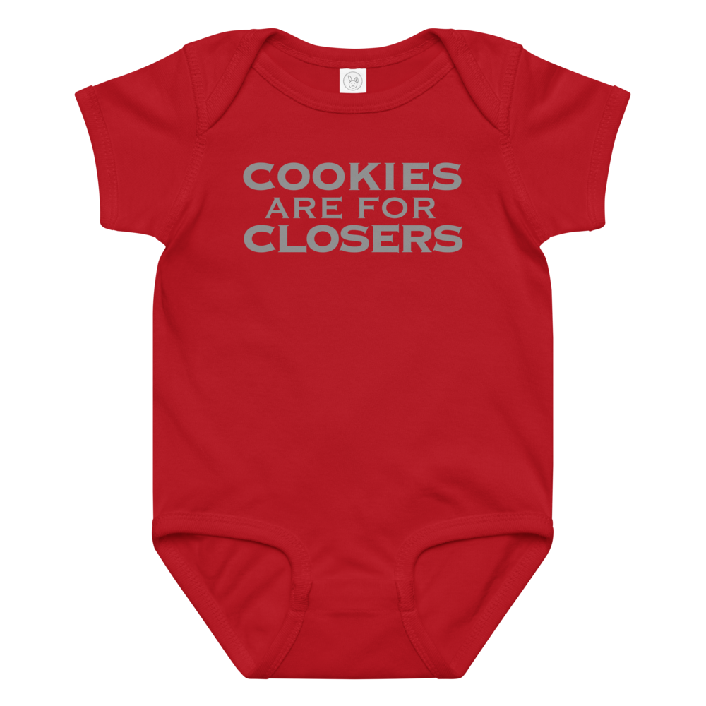 "Cookies Are For Closers" printed on a red baby jersey bodysuit laying on a flat surface amongst other clothes
