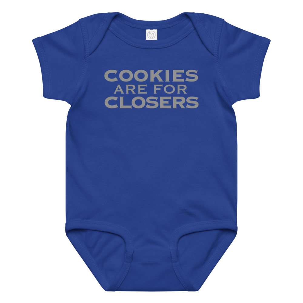 "Cookies Are For Closers" printed on a royal baby jersey bodysuit laying on a flat surface amongst other clothes