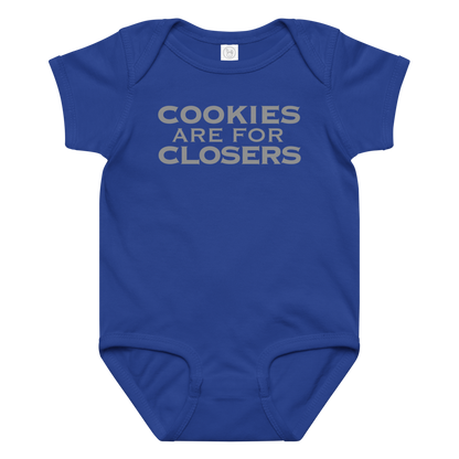 "Cookies Are For Closers" printed on a royal baby jersey bodysuit laying on a flat surface amongst other clothes