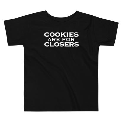 "Cookies Are For Closers" printed on a black toddler short sleeve tee laying on a flat surface