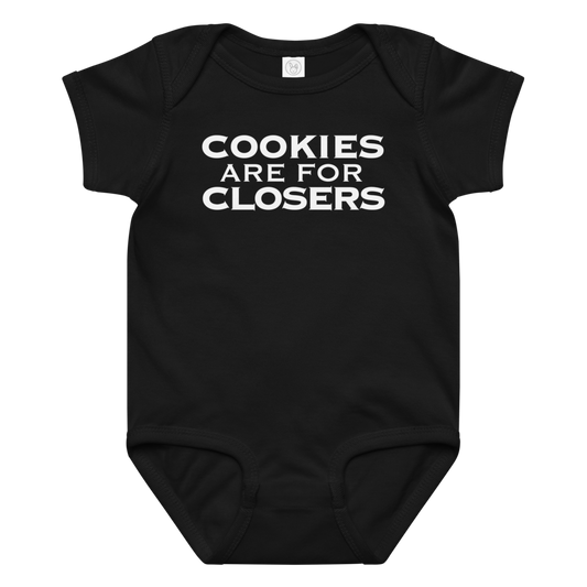 "Cookies Are For Closers" printed on a black baby jersey bodysuit laying on a flat surface amongst other clothes