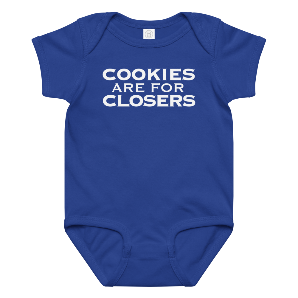 "Cookies Are For Closers" printed on a royal baby jersey bodysuit laying on a flat surface amongst other clothes