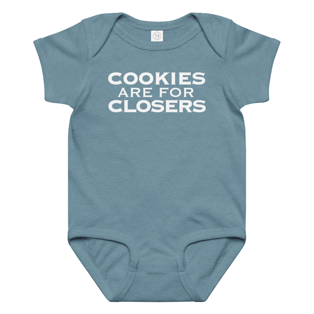 "Cookies Are For Closers" printed on a vintage indigo baby jersey bodysuit laying on a flat surface amongst other clothes