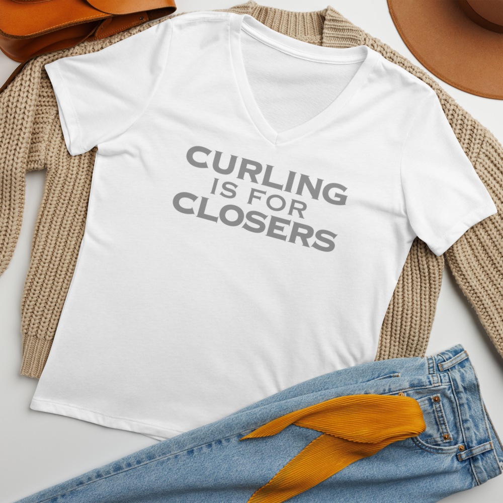 "Curling Is For Closers" printed on a solid white blend women's relaxed v-neck t-shirt laying on a flat surface amongst other clothes
