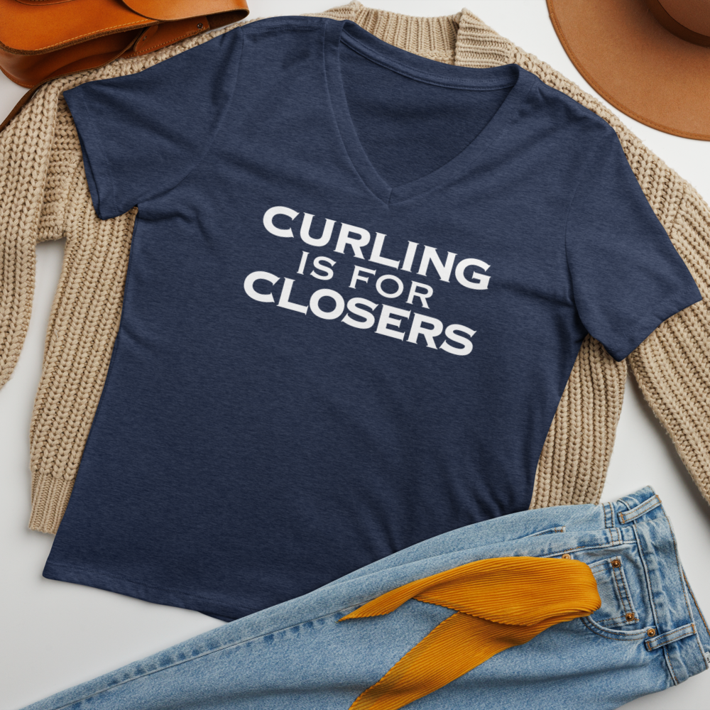 "Curling Is For Closers" printed on a heather navy women's relaxed v-neck t-shirt laying on a flat surface amongst other clothes