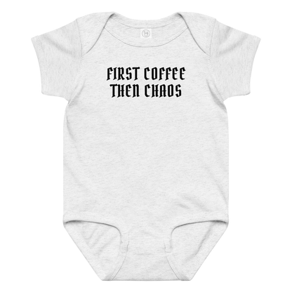 "First Coffee  Then Chaos" printed on a ash baby jersey bodysuit laying on a flat surface amongst other clothes