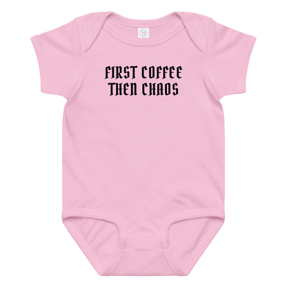 "First Coffee  Then Chaos" printed on a pink baby jersey bodysuit laying on a flat surface amongst other clothes