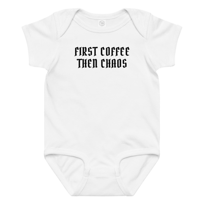 "First Coffee  Then Chaos" printed on a white baby jersey bodysuit laying on a flat surface amongst other clothes