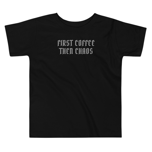 "First Coffee  Then Chaos" printed on a black toddler short sleeve tee laying on a flat surface
