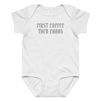 "First Coffee  Then Chaos" printed on a ash baby jersey bodysuit laying on a flat surface amongst other clothes