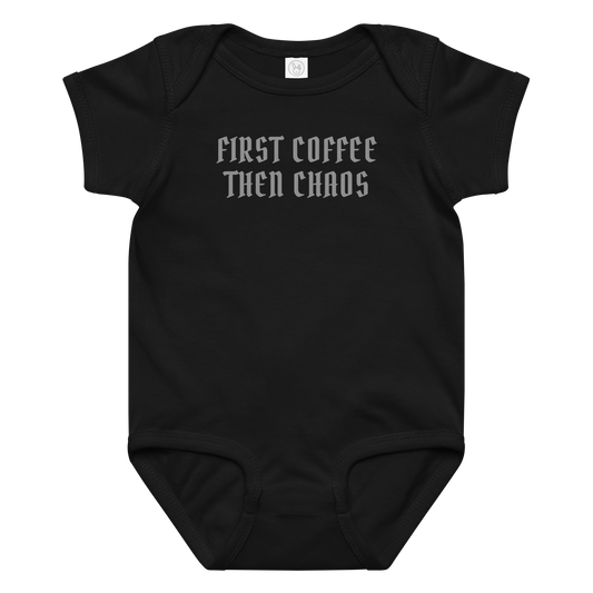 "First Coffee  Then Chaos" printed on a black baby jersey bodysuit laying on a flat surface amongst other clothes