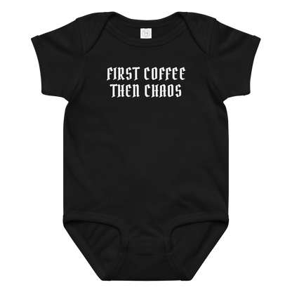 "First Coffee  Then Chaos" printed on a black baby jersey bodysuit laying on a flat surface amongst other clothes