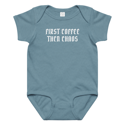 "First Coffee  Then Chaos" printed on a vintage indigo baby jersey bodysuit laying on a flat surface amongst other clothes