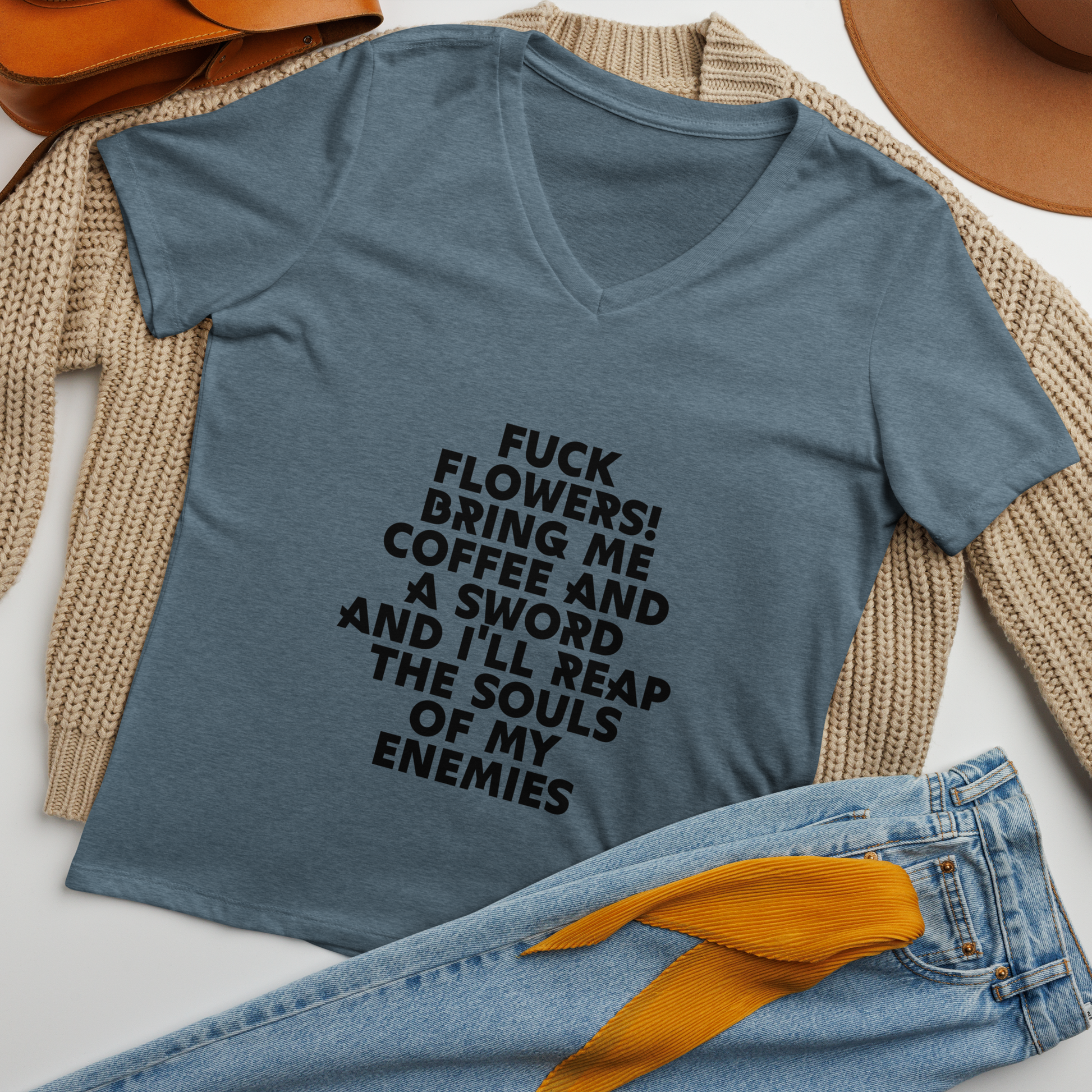 "Fuck Flowers! Bring Me Coffee And A Sword And I'll Reap The Souls Of My Enemies" printed on a heather slate women's relaxed v-neck t-shirt laying on a flat surface amongst other clothes