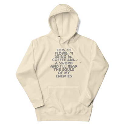 "Forget Flowers! Bring Me Coffee And A Sword And I'll Reap The Souls Of My Enemies" printed on a bone unisex hoodie laying on a flat surface with the hood up