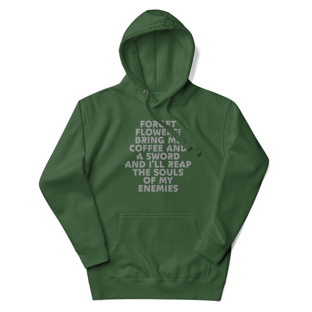 "Forget Flowers! Bring Me Coffee And A Sword And I'll Reap The Souls Of My Enemies" printed on a forest green unisex hoodie laying on a flat surface with the hood up