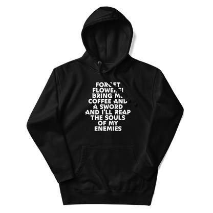 "Forget Flowers! Bring Me Coffee And A Sword And I'll Reap The Souls Of My Enemies" printed on a black unisex hoodie laying on a flat surface with the hood up