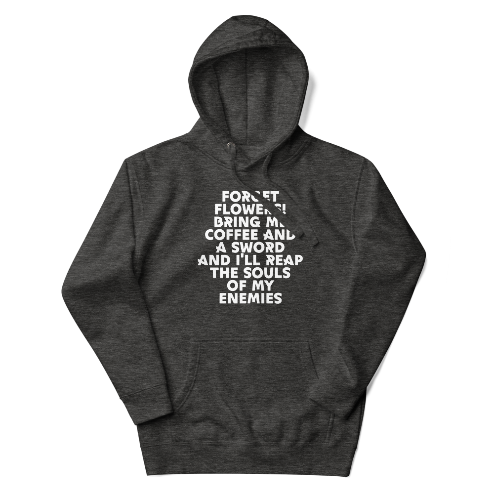 "Forget Flowers! Bring Me Coffee And A Sword And I'll Reap The Souls Of My Enemies" printed on a charcoal heather unisex hoodie laying on a flat surface with the hood up