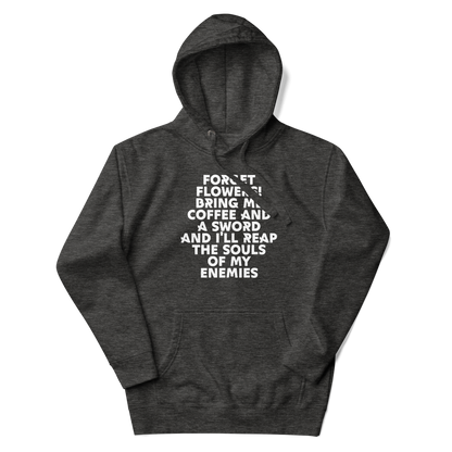 "Forget Flowers! Bring Me Coffee And A Sword And I'll Reap The Souls Of My Enemies" printed on a charcoal heather unisex hoodie laying on a flat surface with the hood up