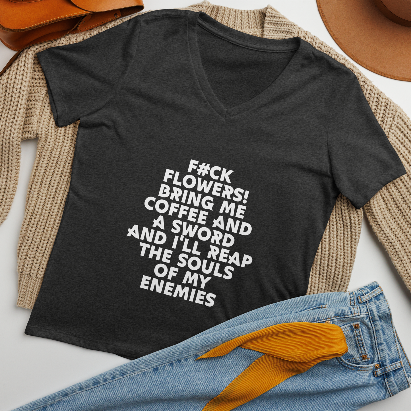 "F#Ck Flowers! Bring Me Coffee And A Sword And I'll Reap The Souls Of My Enemies" printed on a dark grey heather women's relaxed v-neck t-shirt laying on a flat surface amongst other clothes