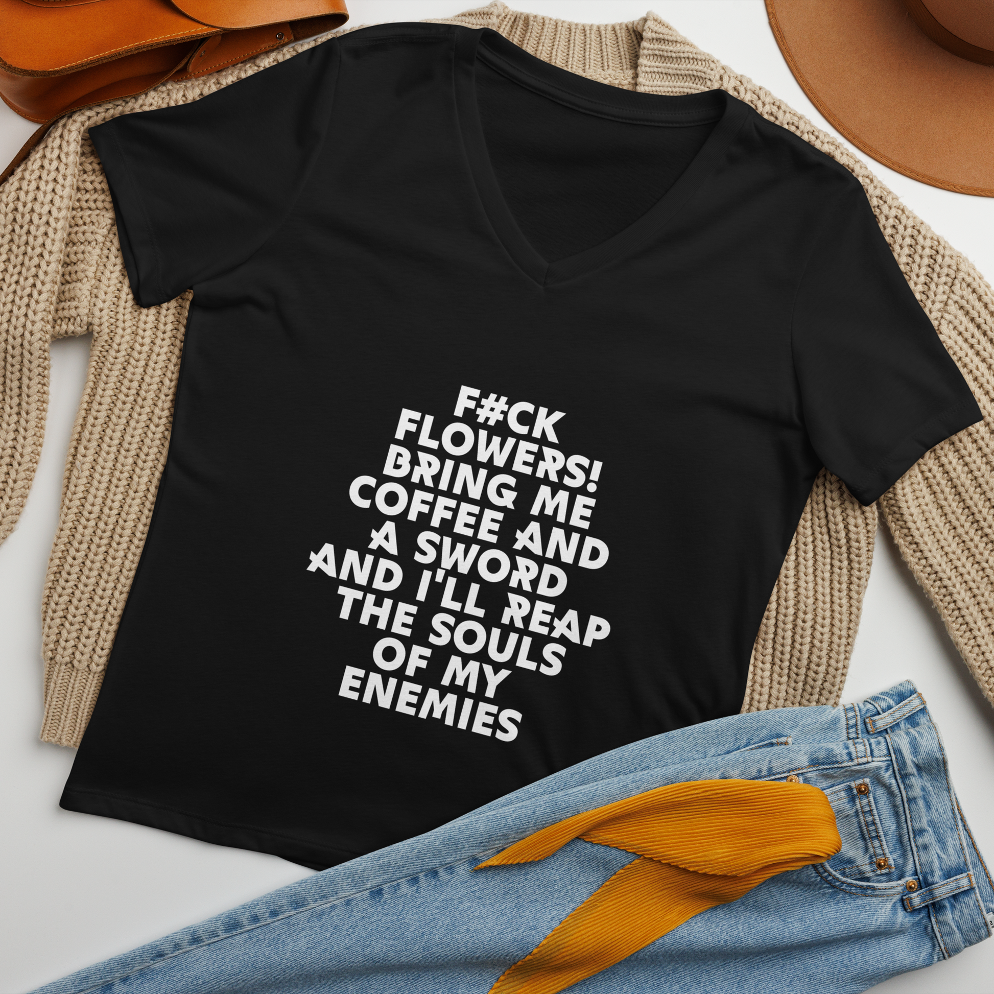 "F#Ck Flowers! Bring Me Coffee And A Sword And I'll Reap The Souls Of My Enemies" printed on a solid black blend women's relaxed v-neck t-shirt laying on a flat surface amongst other clothes