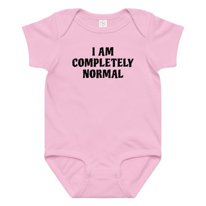 "I am completely normal" printed on a pink baby jersey bodysuit laying on a flat surface amongst other clothes