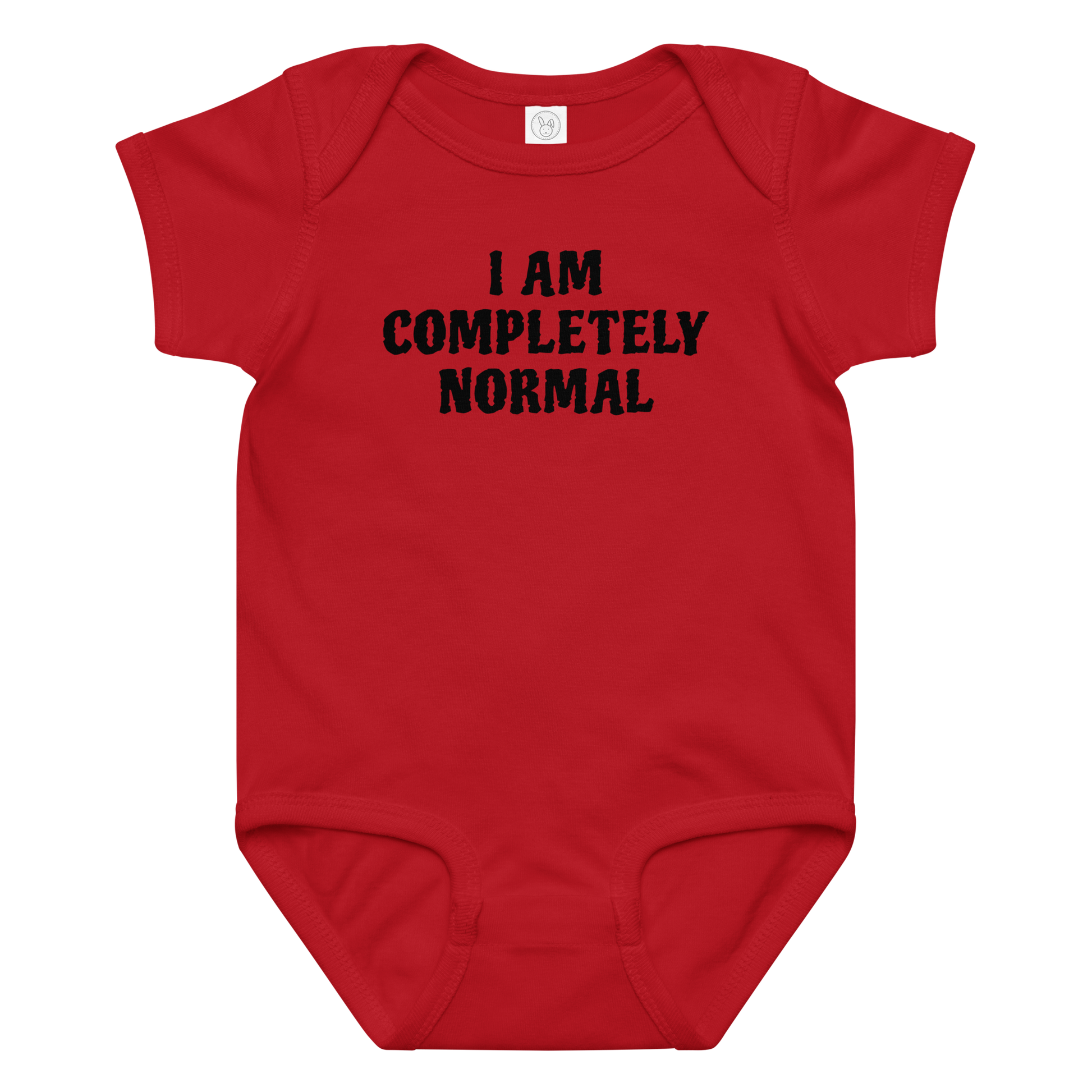 "I am completely normal" printed on a red baby jersey bodysuit laying on a flat surface amongst other clothes