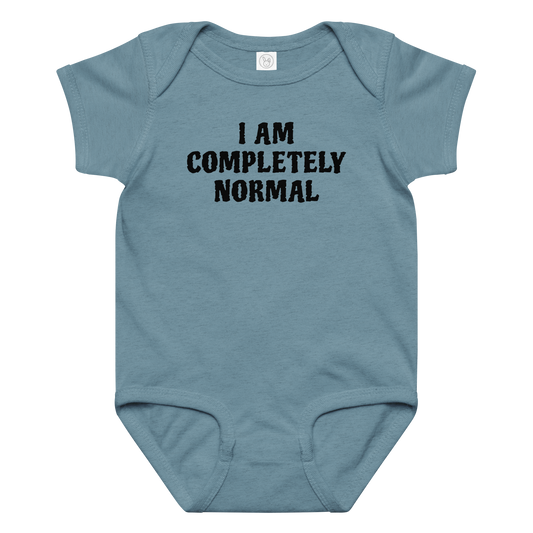 "I am completely normal" printed on a vintage indigo baby jersey bodysuit laying on a flat surface amongst other clothes