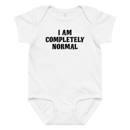 "I am completely normal" printed on a white baby jersey bodysuit laying on a flat surface amongst other clothes