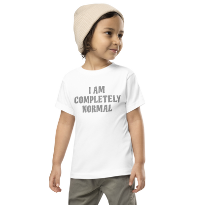 "I am completely normal" printed on a white toddler short sleeve tee worn by a male wearing a cap