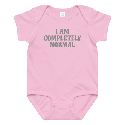 "I am completely normal" printed on a pink baby jersey bodysuit laying on a flat surface amongst other clothes