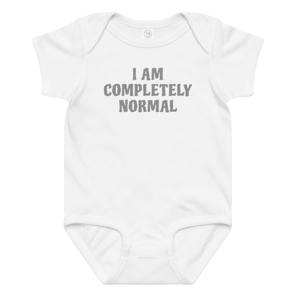 "I am completely normal" printed on a white baby jersey bodysuit laying on a flat surface amongst other clothes