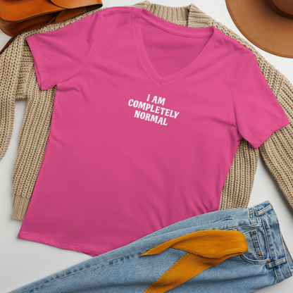 "I am completely normal" printed on a berry women's relaxed v-neck t-shirt laying on a flat surface amongst other clothes