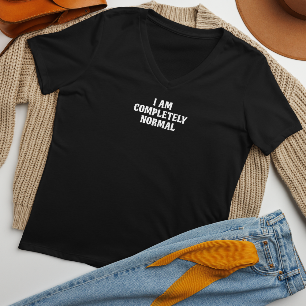 "I am completely normal" printed on a solid black blend women's relaxed v-neck t-shirt laying on a flat surface amongst other clothes