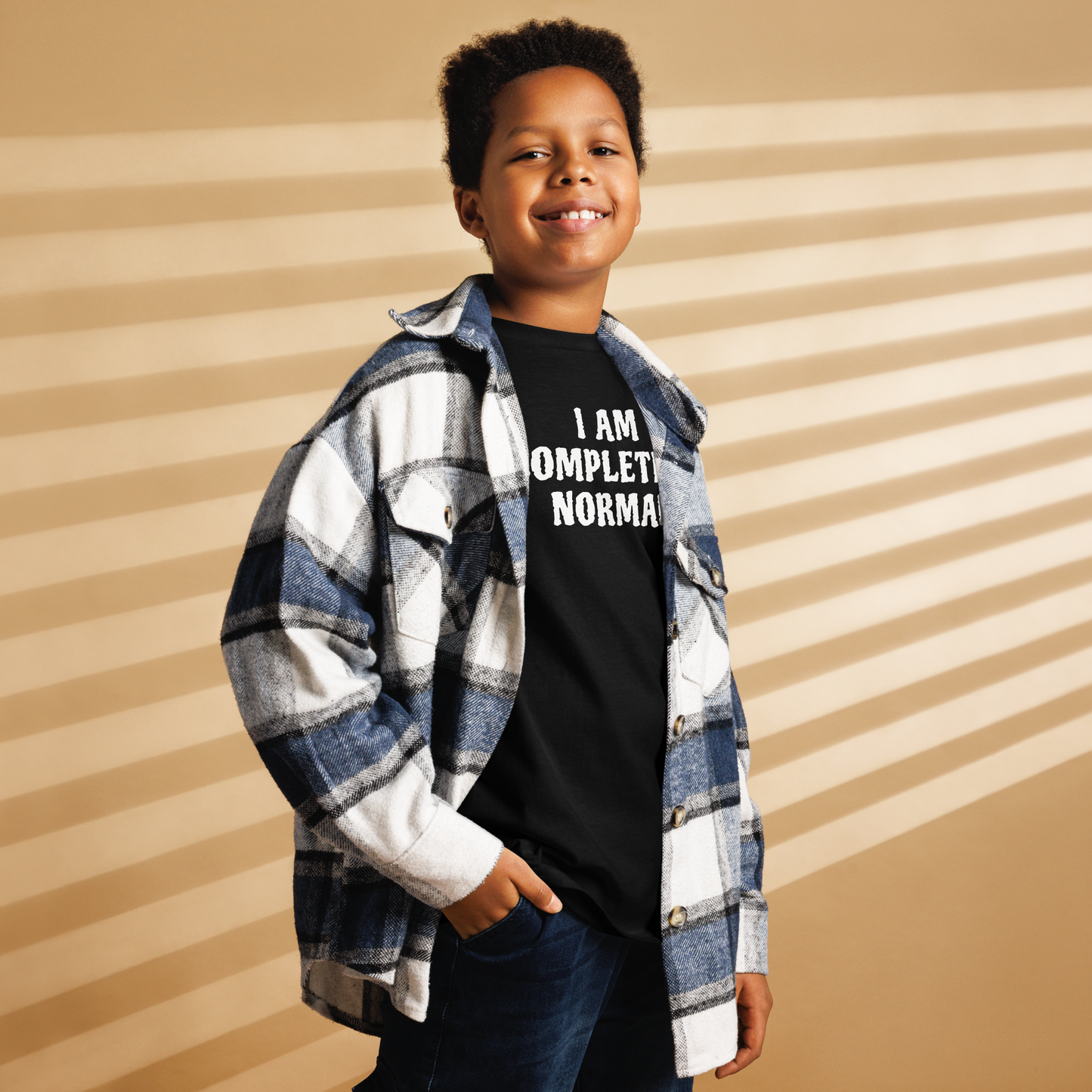 "I am completely normal" printed on a black youth classic tee worn by a male also wearing a jacket