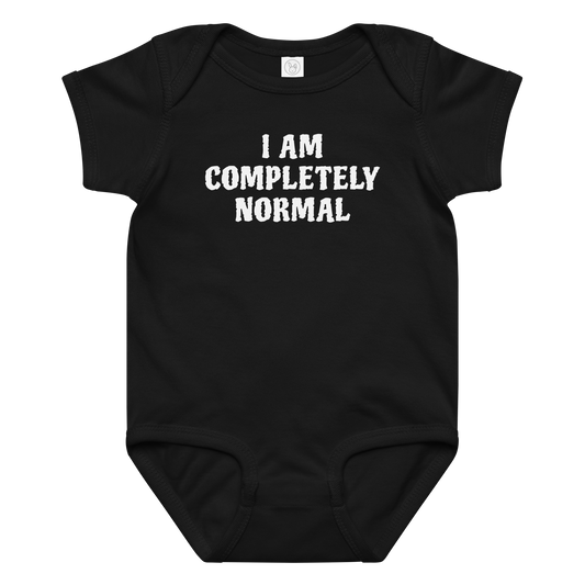 "I am completely normal" printed on a black baby jersey bodysuit laying on a flat surface amongst other clothes
