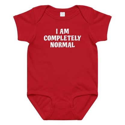 "I am completely normal" printed on a red baby jersey bodysuit laying on a flat surface amongst other clothes