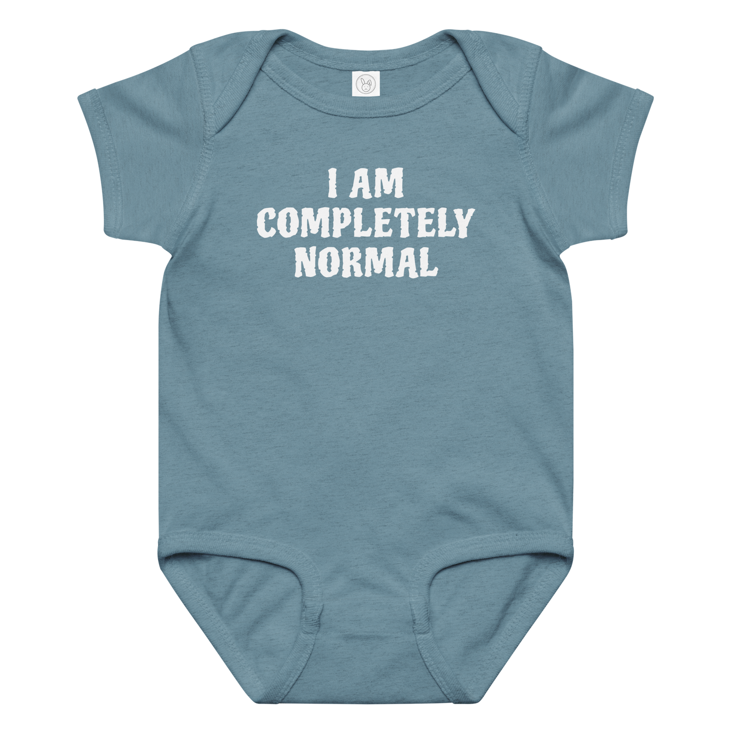 "I am completely normal" printed on a vintage indigo baby jersey bodysuit laying on a flat surface amongst other clothes