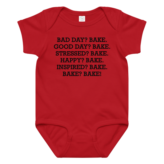 "Bad Day? Bake. Good Day? Bake. Stressed? Bake. Happy? Bake. Inspired? Bake. Bake? Bake!" printed on a red baby jersey bodysuit laying on a flat surface amongst other clothes