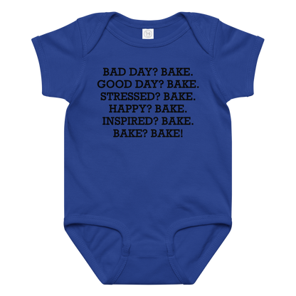 "Bad Day? Bake. Good Day? Bake. Stressed? Bake. Happy? Bake. Inspired? Bake. Bake? Bake!" printed on a royal baby jersey bodysuit laying on a flat surface amongst other clothes