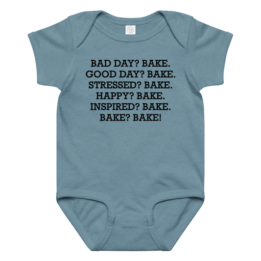 "Bad Day? Bake. Good Day? Bake. Stressed? Bake. Happy? Bake. Inspired? Bake. Bake? Bake!" printed on a vintage indigo baby jersey bodysuit laying on a flat surface amongst other clothes