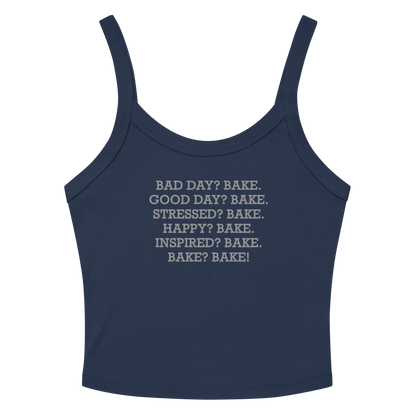 "Bad Day? Bake. Good Day? Bake. Stressed? Bake. Happy? Bake. Inspired? Bake. Bake? Bake!" printed on a solid navy blend women's micro-rib tanktop laying on a flat surface amongst sunglasses and shorts