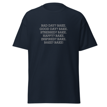 "Bad Day? Bake. Good Day? Bake. Stressed? Bake. Happy? Bake. Inspired? Bake. Bake? Bake!" printed on a navy unisex classic tee laying on a flat surface