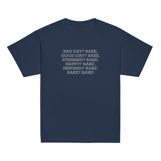 "Bad Day? Bake. Good Day? Bake. Stressed? Bake. Happy? Bake. Inspired? Bake. Bake? Bake!" printed on a navy youth classic tee laying on a flat surface