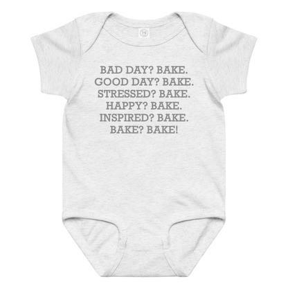 "Bad Day? Bake. Good Day? Bake. Stressed? Bake. Happy? Bake. Inspired? Bake. Bake? Bake!" printed on a ash baby jersey bodysuit laying on a flat surface amongst other clothes